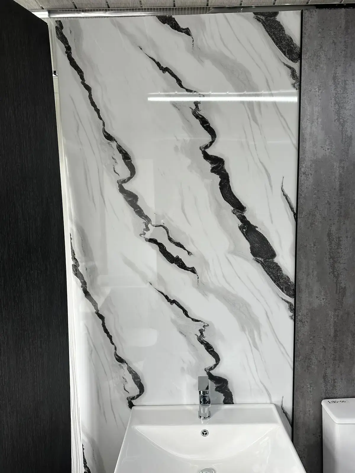 a bathroom with a white sink and a black and white marble wall